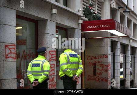 Polizisten beobachten einen Aktivisten, der auf dem Vordach von Leonardos Büros sitzt. Aktivisten der Palästinensischen Aktion besetzen und zielen den italienischen Rüstungsgiganten Leonardo in ihrem Londoner Hauptquartier und schließen sie ab. Leonardo beliefert Israel mit Kampfjets und Waffen, die derzeit im Gazastreifen eingesetzt werden. Die Palästinensische Aktion verlangt, dass Waffenunternehmen, die Waffen für Israel bereitstellen, dauerhaft stillgelegt werden. Sie haben angekündigt, dass Unternehmen, die Waffen an die israelischen Streitkräfte verkaufen, und ihre Partnerunternehmen mit direkten Maßnahmen ins Visier genommen werden. Diese Aktionen sollen hervorgehoben werden Stockfoto