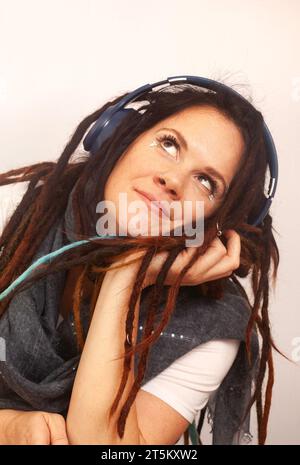 Alternative Bohemian Frau mit Dreadlocks und Kopfhörern. Verspieltes Aufschauen Stockfoto