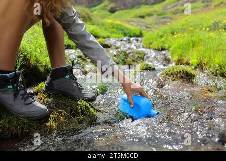 Nahaufnahme eines Wanderers, der in einem Bach im Berg eine Kantine füllt Stockfoto