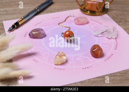 Astrologie-Vorhersage. Zodiac-Rad, Edelsteine und Pendel auf Holztisch, Nahaufnahme Stockfoto