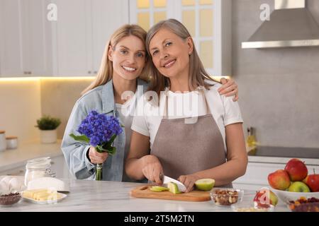 Tochter mit schönen Kornblumen besucht ihre reife Mutter zu Hause Stockfoto