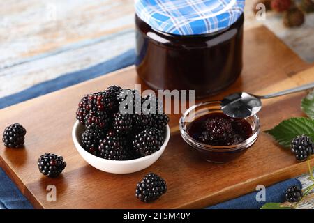 Frische reife Brombeeren, leckere Marmelade und Blätter auf dem Tisch, Nahaufnahme Stockfoto