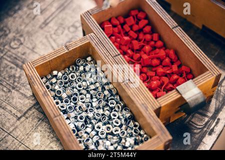 Metallmutter mit metrischem Gewinde in Holzkiste. Metallzubehör zur Montage von Metallteilen Stockfoto