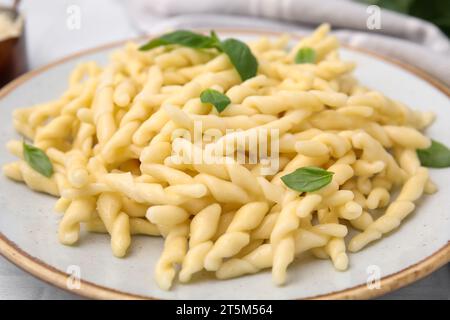 Teller mit köstlicher Trofie-Pasta mit Basilikumblättern auf dem Tisch, Nahaufnahme Stockfoto