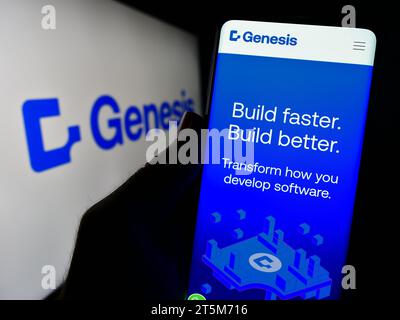 Person, die ein Mobiltelefon mit Website des britischen Fintech-Unternehmens Genesis Global Technology Limited mit Logo hält. Konzentrieren Sie sich auf die Mitte des Telefondisplays. Stockfoto