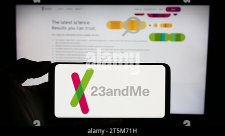 Person mit Smartphone und Logo des US-Biotechnologie-Unternehmens 23andMe Inc. Vor der Website. Schwerpunkt auf dem Display des Telefons. Stockfoto