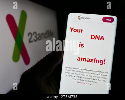 Person, die ein Mobiltelefon hält, mit der Webseite des US-Biotechnologie-Unternehmens 23andMe Inc. Vor dem Geschäftslogo. Konzentrieren Sie sich auf die Mitte des Telefondisplays. Stockfoto