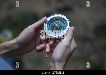 Zugeschnittene Aufnahme einer Reisenden, die während der Wanderung im Wald durch Kompass navigiert Stockfoto