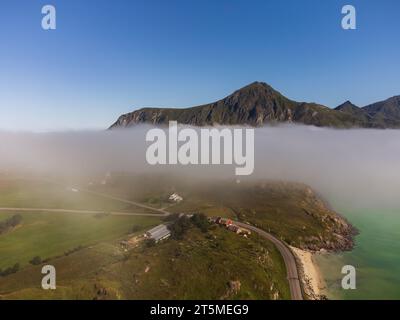 Blick von oben auf eine wunderschöne Landschaft eines Sees in den Bergen Norwegens, mit Nebel, der hereinbricht. E10 Richtung Flakstad. Stockfoto