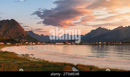 Sonnenuntergang über einem Strand in Lofoten, Rambergstranda, im Sommer, in der Nähe von Ramberg. Überwiegend klarer Himmel, hohe Berge und ferne Fjorde. Pinke Wolken. Stockfoto