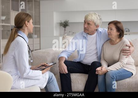 Junger Arzt besucht glückliches reifes älteres Patientenpaar Stockfoto