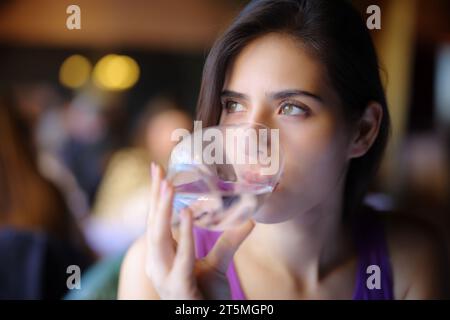 Abgelenkte Frau, die Wasser in einem Restaurant trinkt Stockfoto