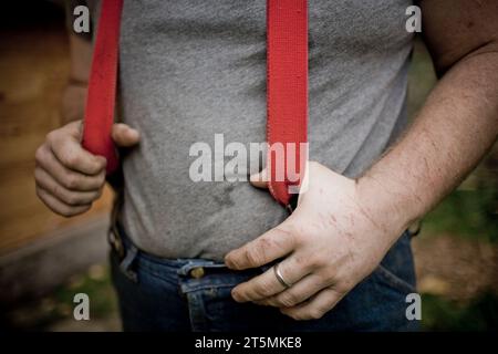 Ein junger Mann mit roten Hosenträgern auf einer Farm. Stockfoto