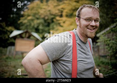 Ein junger Mann mit roten Hosenträgern auf einer Farm. Stockfoto