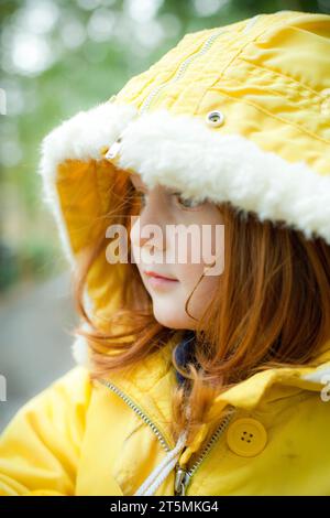 Ein rothaariges Mädchen, das sich für kaltes Wetter zusammengebündelt hat. Stockfoto