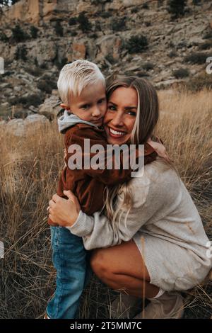 Mutter umarmt den vierjährigen Sohn an einem schönen Herbsttag. Stockfoto