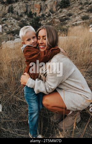 Mutter umarmt den vierjährigen Sohn an einem schönen Herbsttag Stockfoto