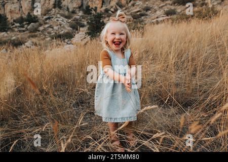 Das zweijährige Mädchen steht draußen und lacht vor Freude." Stockfoto