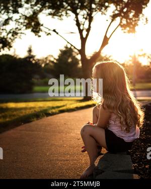 Schönes kleines Mädchen mit langen Locken im Sommer Stockfoto