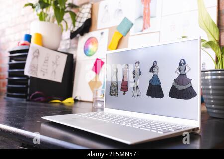 Laptop mit Projekten auf dem Schreibtisch im sonnigen Modestudio Stockfoto
