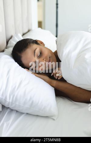 Glückliche Frau, die auf weißen Kissen im Schlafzimmer schläft Stockfoto