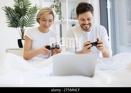 Vorderansicht eines kaukasiers, der Videospiele spielt, während er zu Hause unter der Decke liegt. Stockfoto
