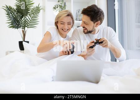 Vorderansicht eines kaukasiers, der Videospiele spielt, während er zu Hause unter der Decke liegt. Stockfoto