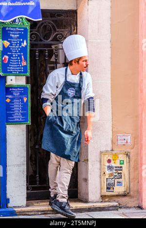 Der Koch mit Haube und Schürze macht eine Raucherpause vor La Creperie Francaise, Rue Dauphine, Paris 6, Frankreich. Stockfoto