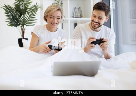 Vorderansicht eines kaukasiers, der Videospiele spielt, während er zu Hause unter der Decke liegt. Stockfoto