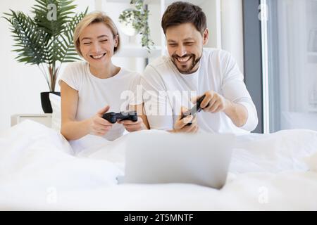 Vorderansicht eines kaukasiers, der Videospiele spielt, während er zu Hause unter der Decke liegt. Stockfoto
