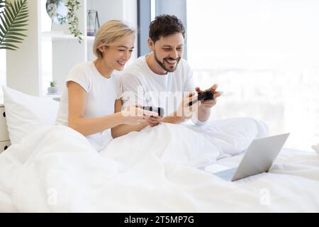Kaukasier spielt Videospiele, während er zu Hause unter der Decke liegt. Stockfoto