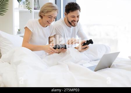 Kaukasier spielt Videospiele, während er zu Hause unter der Decke liegt. Stockfoto