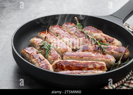 Köstliche Schweinefleischwürste in einer Pfanne auf grauem Hintergrund Stockfoto