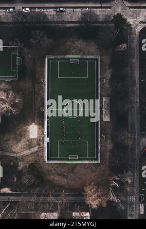 Blick von oben auf ein kleines Trainingsfußballfeld in der Stadt. Fußballplatz mit Kunstrasen in urbaner Umgebung an kalten Wintertagen ohne Schnee. Stockfoto