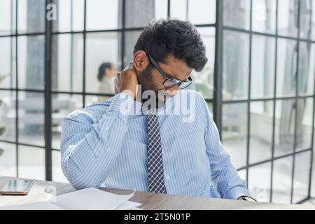 Er hat Schulterschmerzen im Nacken- und Rückenbereich und Überstunden Stockfoto