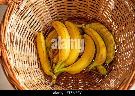 Halten Sie mit den Händen einen Rattankorb mit Bananen Stockfoto