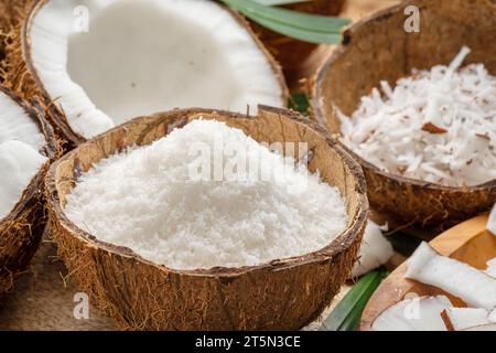 Frisch geöffnete Kokosnüsse zusammen mit Kokosscheiben, Flocken und Kokosblättern auf einem Holztisch. Schöner Hintergrund für Ihre Projekte. Stockfoto