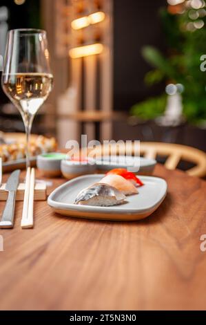 Nigiri-Set: Makrele, Wolfsbarsch, Lachs auf einem Teller auf einem Tisch in einer Sushi-Bar auf einem Teller. Hochwertige Fotos Stockfoto