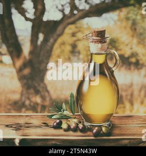 Eine Flasche handgefertigtes Olivenöl steht auf einem Holztisch, hinter einem Olivengarten an einem etwas Bokeh, sonnigen Tag. Bild im Vintage-Stil. Stockfoto