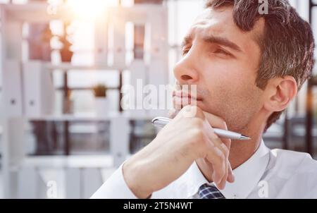 Nahaufnahme. Ein nachdenklicher junger Geschäftsmann im Büro, der wegschaut. Stockfoto