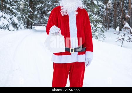 Der Weihnachtsmann im Winter im Freien und im Schnee in Papiertaschen mit Kunsthandwerk und Essenslieferung. Einkaufen, Verpackungsrecycling, handgefertigt, Lieferung für Stockfoto