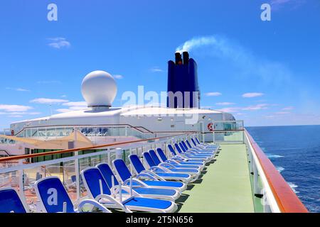 Während das P&O-Kreuzfahrtschiff Aurora nach Lissabon segelt, warten Nardi Sonnenliegen auf Sonnenanbeter auf dem Sonnendeck mit Blick auf den Riviera Swimmingpool im April 2022. Stockfoto