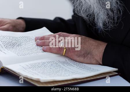 Ein Mann legt die Ringe der Braut und des Bräutigams an seine Finger, um sie vor der Ringtauschzeremonie bei einer jüdischen Hochzeit zu verwahren. Stockfoto