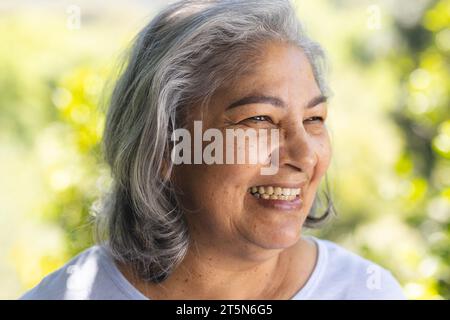 Porträt einer glücklichen zweirassigen Seniorin, die im sonnigen Garten lacht, Kopierraum Stockfoto