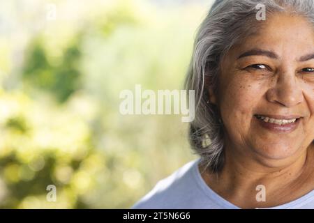 Halbgesicht einer glücklichen, birassischen Seniorin, die im sonnigen Garten lächelt, Kopierraum Stockfoto