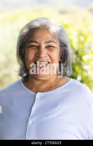 Porträt einer glücklichen zweirassigen Seniorin, die im sonnigen Garten lacht, Kopierraum Stockfoto