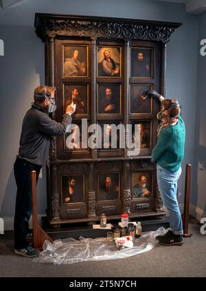 Die Konservatoren David Everingham und Alison Aynesworth arbeiten an der Restaurierung von 12 ölbemalten Tafeln auf dem Schrank des Apostels, die im Bronte Parsonage Museum in Haworth ausgestellt sind. Die Ölmalerkonservatoren arbeiten 12 Wochen damit, die Gemälde auf dem Schrank zu restaurieren, der von Charlotte Bronte in Jane Eyre beschrieben wird. Bilddatum: Montag, 6. November 2023. Stockfoto