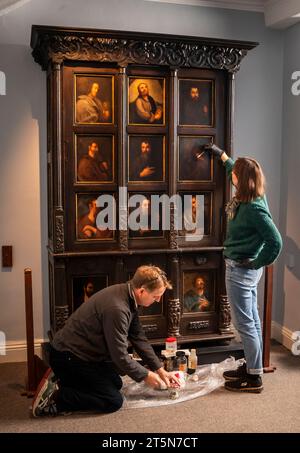 Die Konservatoren David Everingham und Alison Aynesworth arbeiten an der Restaurierung von 12 ölbemalten Tafeln auf dem Schrank des Apostels, die im Bronte Parsonage Museum in Haworth ausgestellt sind. Die Ölmalerkonservatoren arbeiten 12 Wochen damit, die Gemälde auf dem Schrank zu restaurieren, der von Charlotte Bronte in Jane Eyre beschrieben wird. Bilddatum: Montag, 6. November 2023. Stockfoto