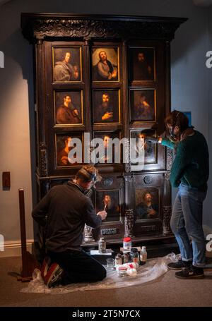 Die Konservatoren David Everingham und Alison Aynesworth arbeiten an der Restaurierung von 12 ölbemalten Tafeln auf dem Schrank des Apostels, die im Bronte Parsonage Museum in Haworth ausgestellt sind. Die Ölmalerkonservatoren arbeiten 12 Wochen damit, die Gemälde auf dem Schrank zu restaurieren, der von Charlotte Bronte in Jane Eyre beschrieben wird. Bilddatum: Montag, 6. November 2023. Stockfoto