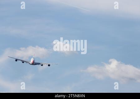 British Airways Airbus A380-841, G-XLEF verlässt London Heathrow in den sonnigen Nachmittag. Ein Kondensstreifen ist von einem anderen Flugzeug aus in der Entfernung sichtbar Stockfoto